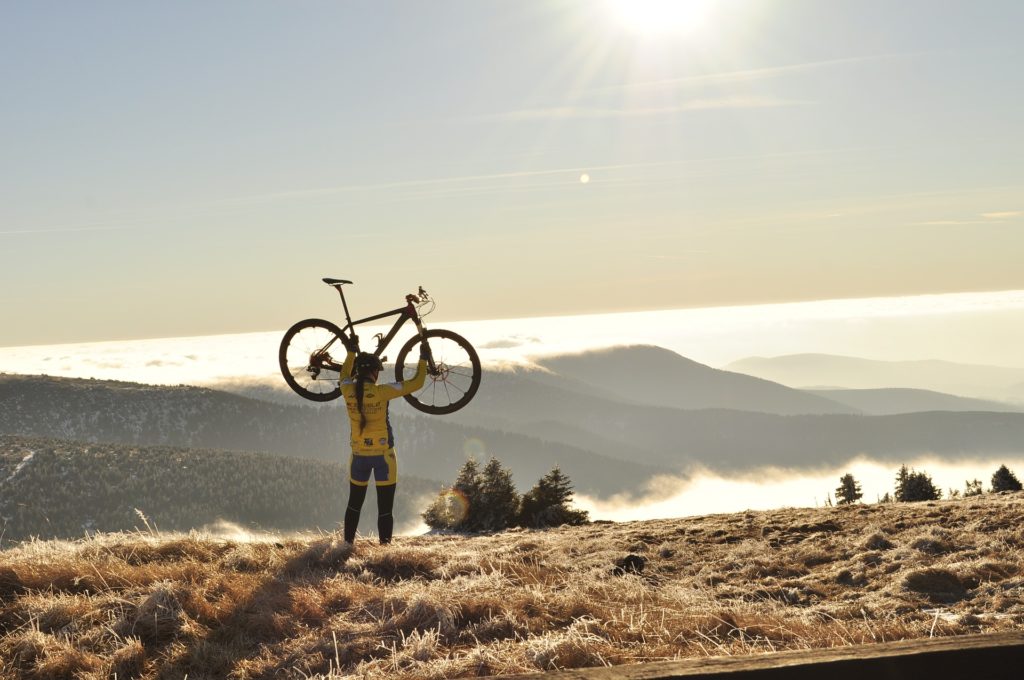 ciclista che alza la sua bicicletta al sole