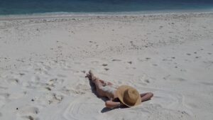 Nudismo in Italia: una ragazza prende il sole distesa su una spiaggia libera deserta