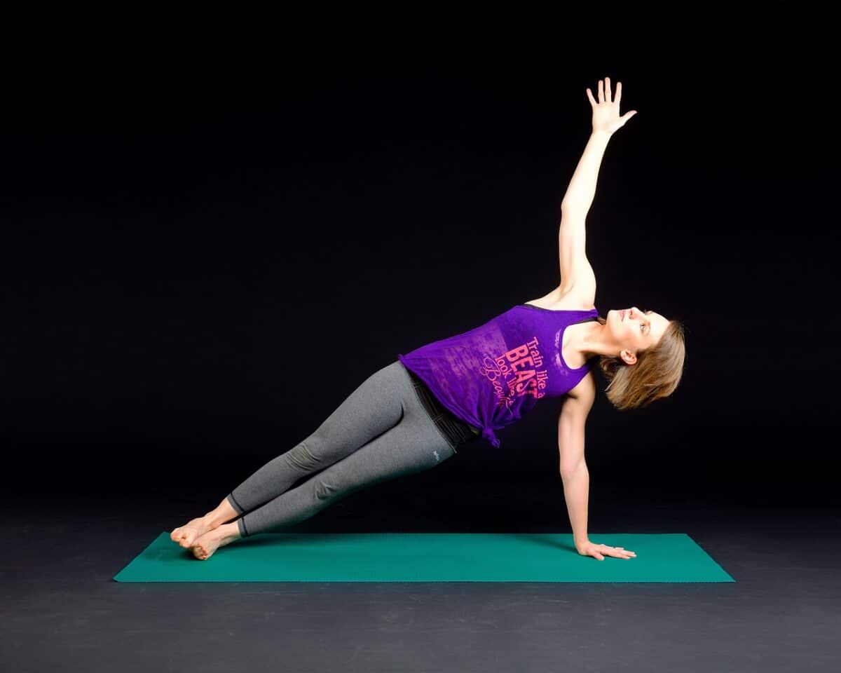 giovane donna su un tappettino che fa esercizio fisico per rafforzare i muscoli con il plank