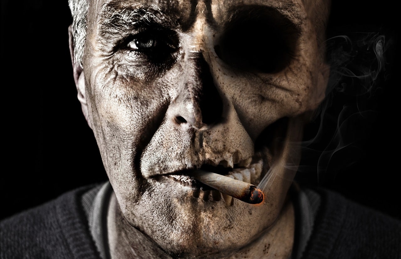immagine crativa faccia uomo con teschio che fuma immagine di un uomo che fuma una sigaretta e si trasforma in un teschio di cadavere per evidenziare i danni che provoca il fumo di tabacco