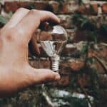 una mano che tiene una lampadina davanti ad un muro