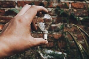 una mano che tiene una lampadina davanti ad un muro